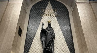 A statue with words behind it to prais to bless to preach