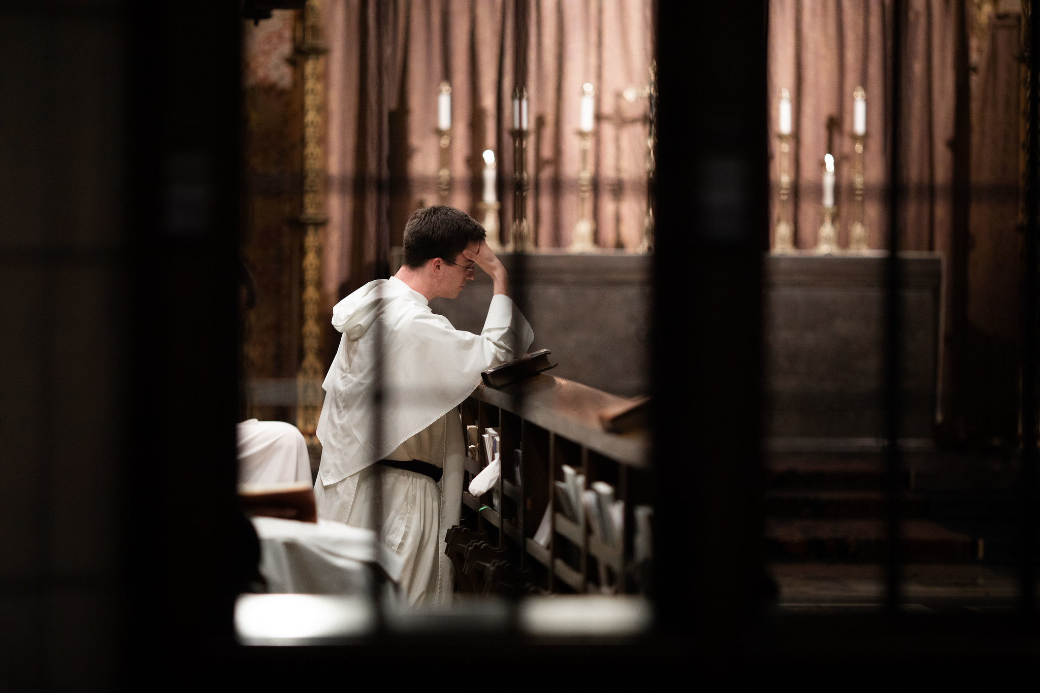 A young Dominican friar kneeling in prayer inside a chapel, contemplating his religious vocation and calling to the Order.